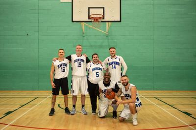 Six Ravens players posing for a team photo beneath the basket